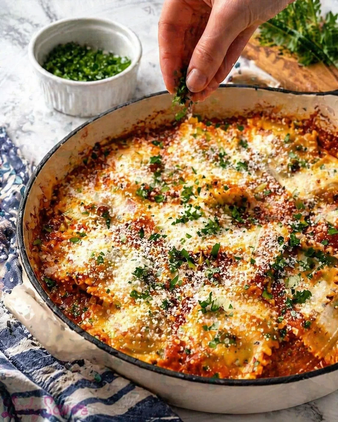 step-process-placeholder-13-13.png Baked ravioli plated, resting with a sprinkle of chopped parsley or basil on top.