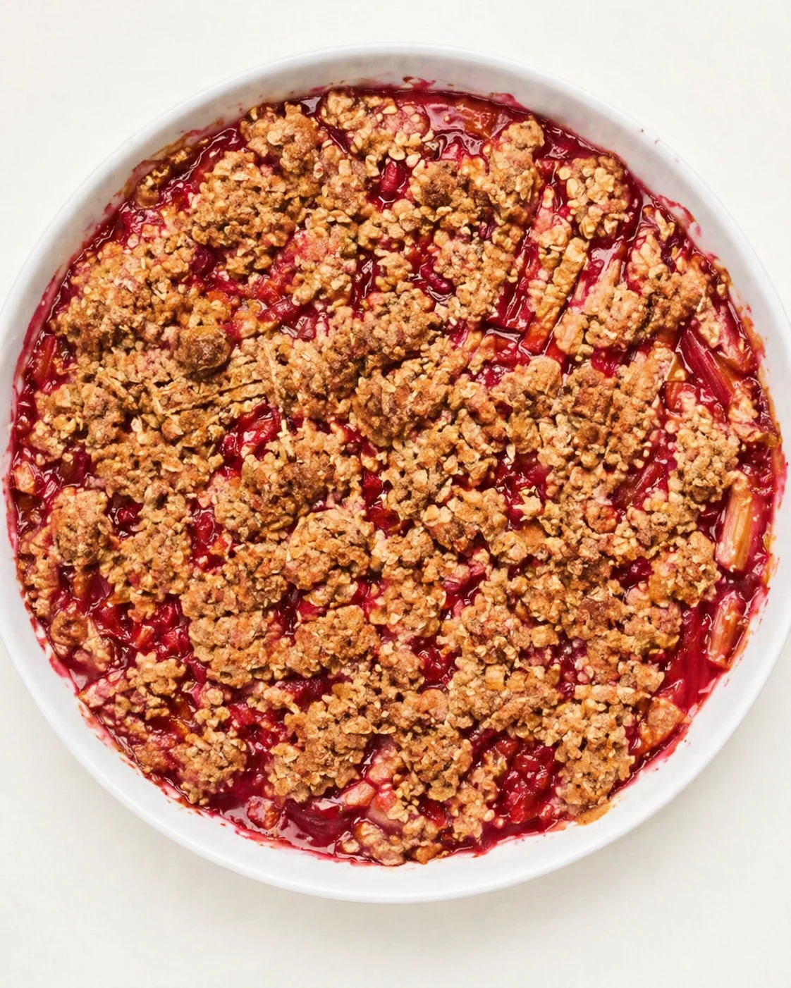 round white baking dish with ruby berry filling and golden crumble topping