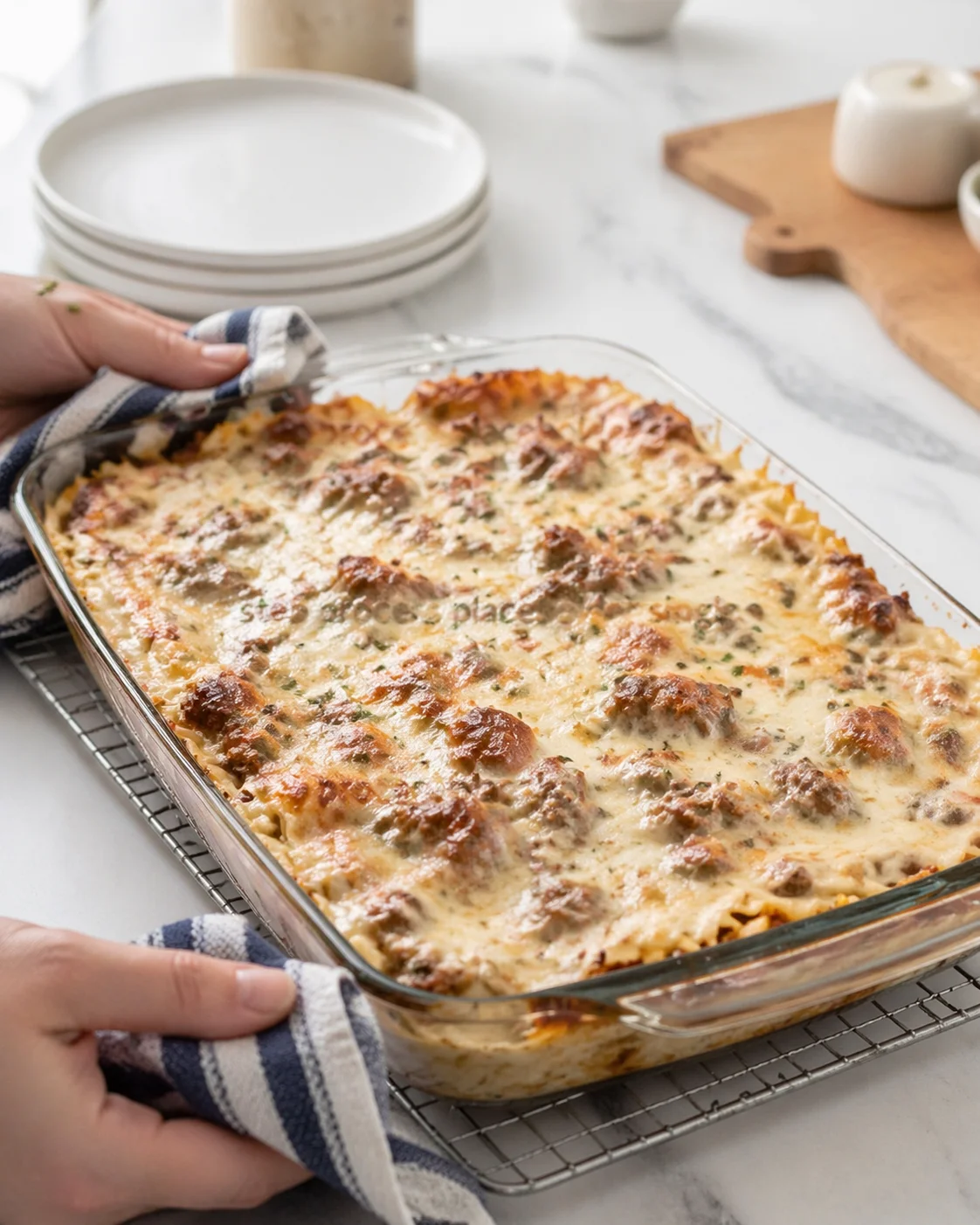 baked cheesy pasta in a clear glass dish on a marble counter