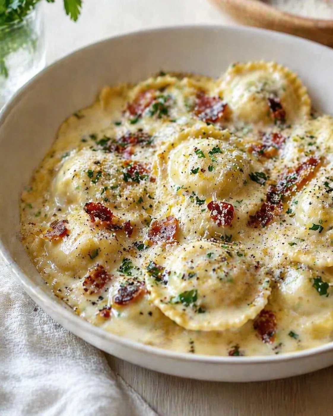 Creamy gnocchi bake in a white dish topped with bacon and parsley