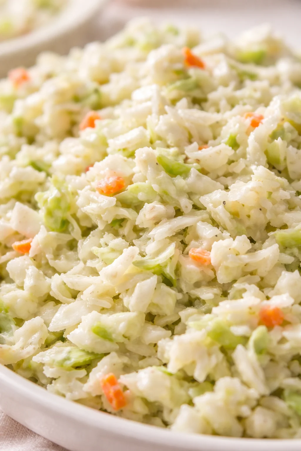 Close-up of creamy potato salad with diced potatoes, celery, and carrot in a white dish