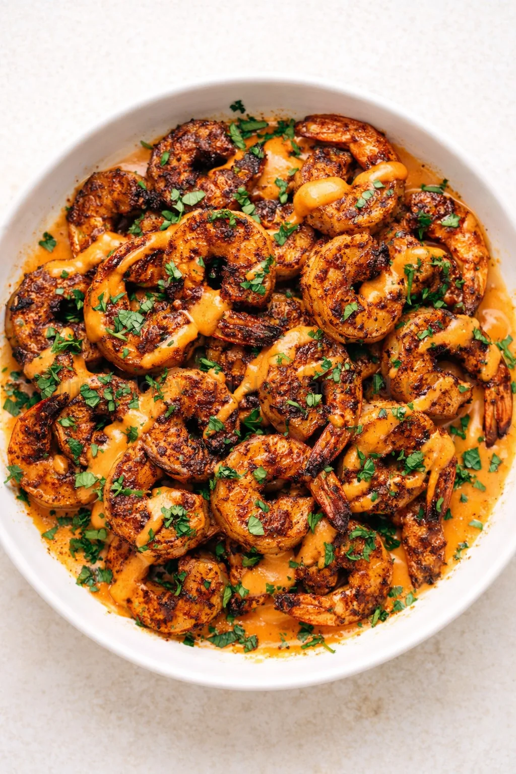 bowl of charred shrimp in orange creamy sauce, garnished with parsley