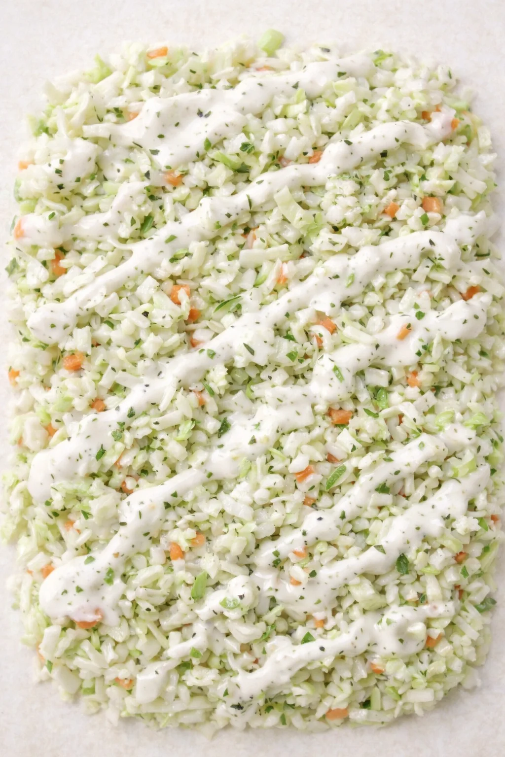 finely chopped celery, onions, and carrots with creamy herb dressing drizzled across a parchment sheet