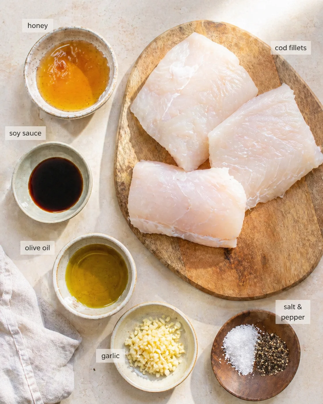 Measured ingredients arranged for Baked Cod with Honey Soy Marinade: 1 lb cod fillets (Look for glossy and firm cod.), 2 tablespoons liquid honey, 1 tablespoon low-sodium soy sauce (Prevents the dish from becoming overly