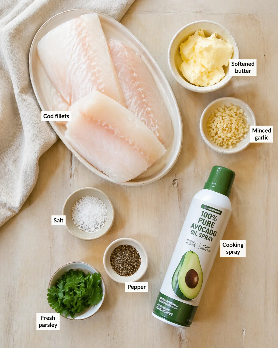 Raw cod fillets on a plate with bowls of butter, minced garlic, salt, pepper, parsley, and avocado oil spray.