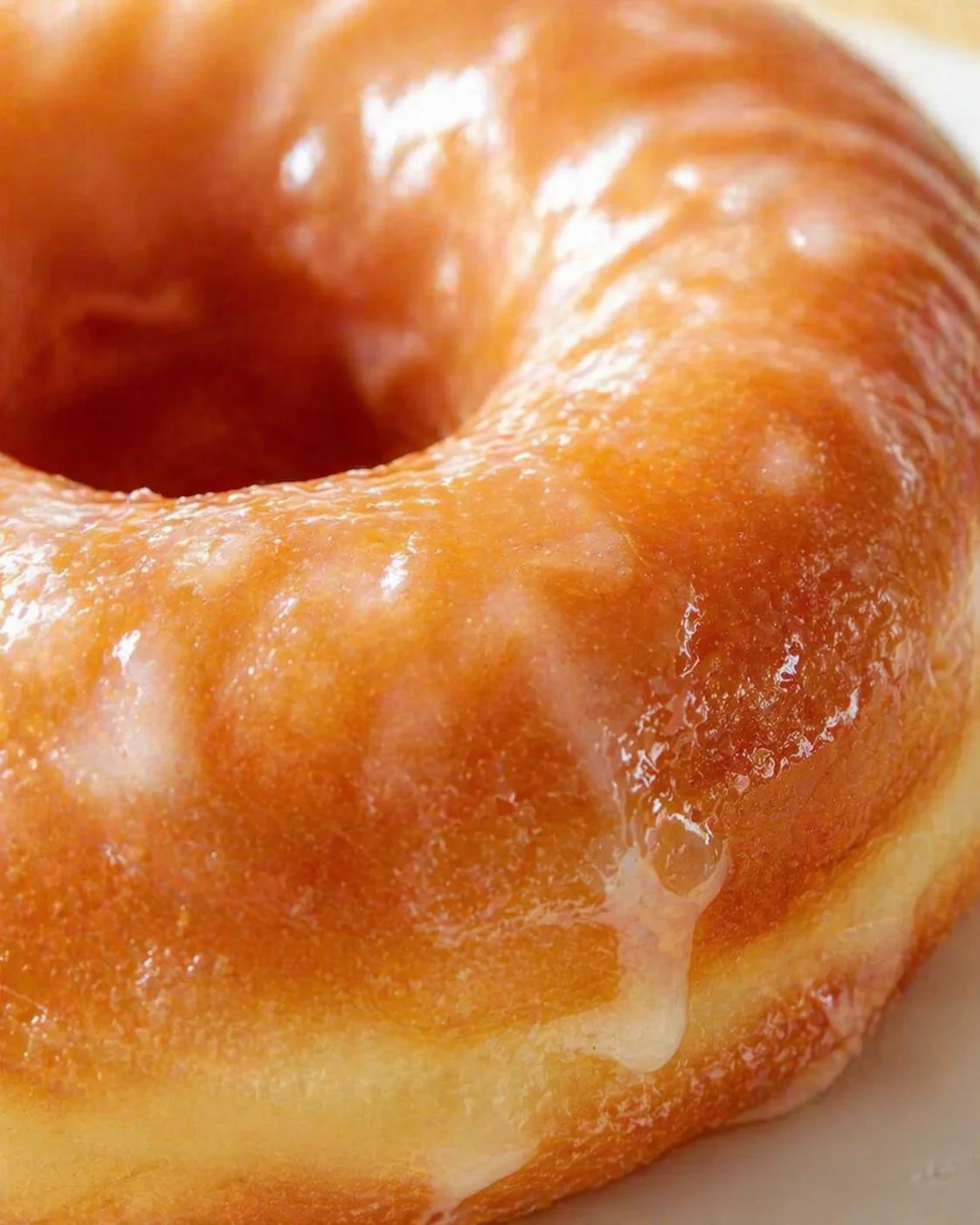 Close-up view of a glossy glazed donut with warm amber glaze.