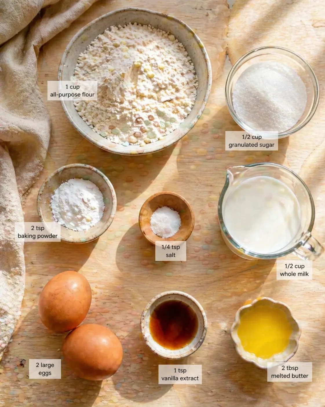 Top-down view of baking ingredients with labeled bowls on a wooden surface.
