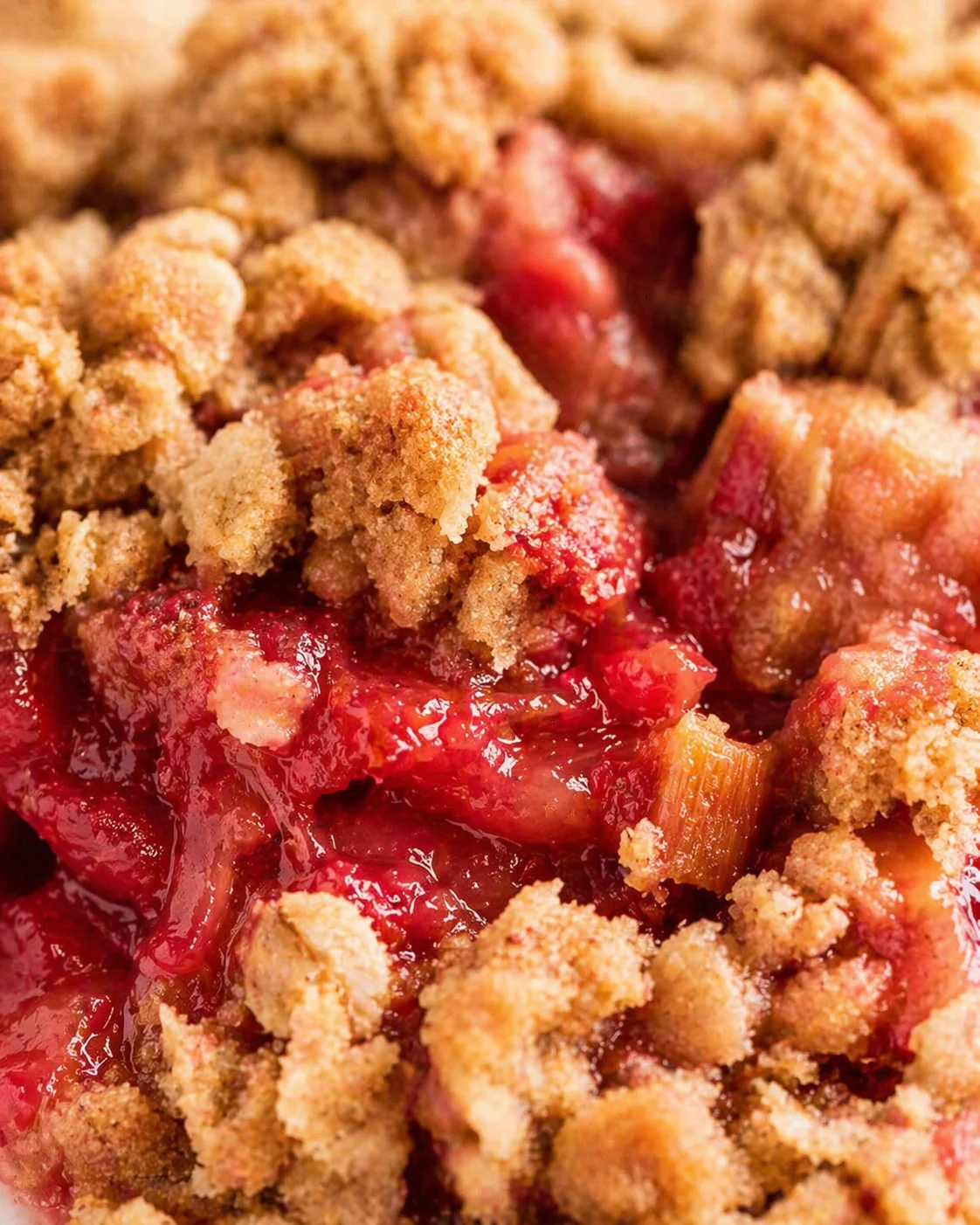 close-up of a berry crumble with golden brown crumbs atop a red fruit filling