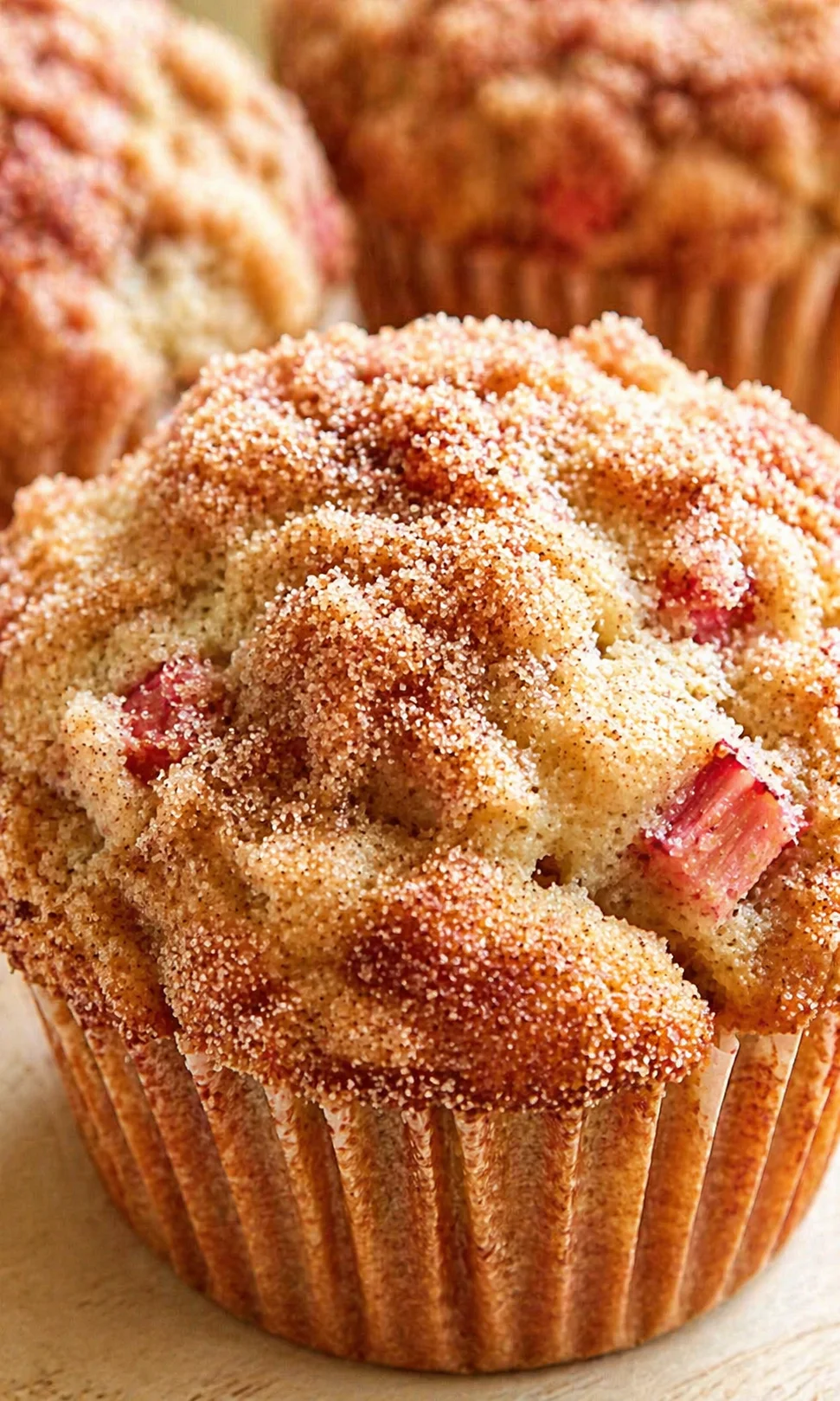Close-up of golden muffins with crumbly sugar topping and visible strawberry bits