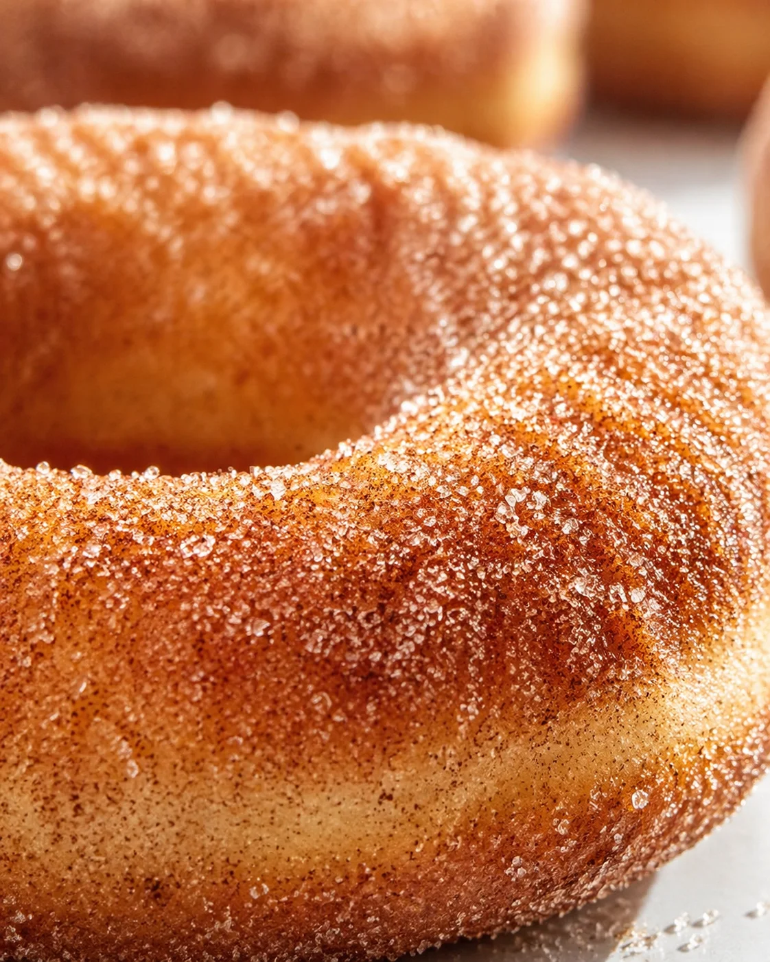 Close-up of a ring-shaped donut coated in coarse sugar crystals.