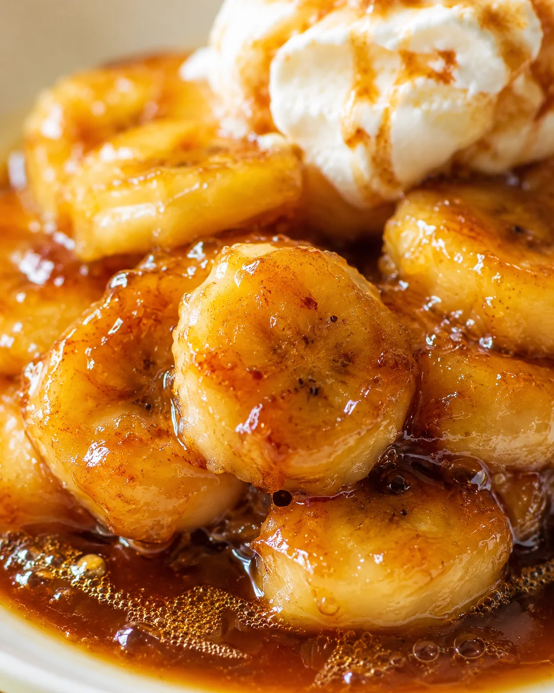 Close-up of caramel-glazed banana slices with a scoop of vanilla ice cream in a bowl