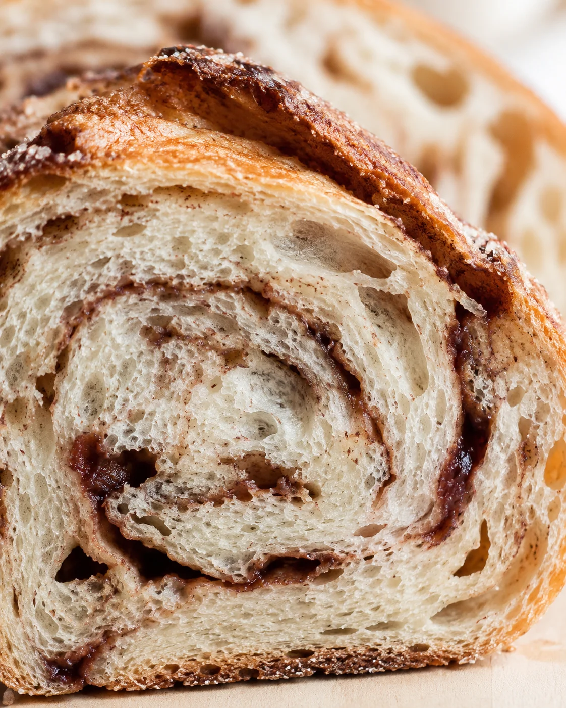 close-up of a cinnamon-swirled bread slice with a golden crust and airy crumb.