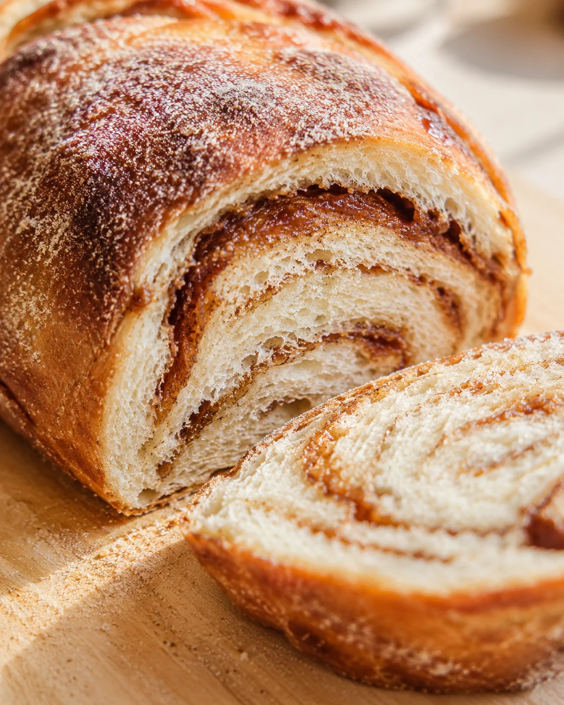Close-up of a golden-brown cinnamon-swirled brioche loaf on a wooden board