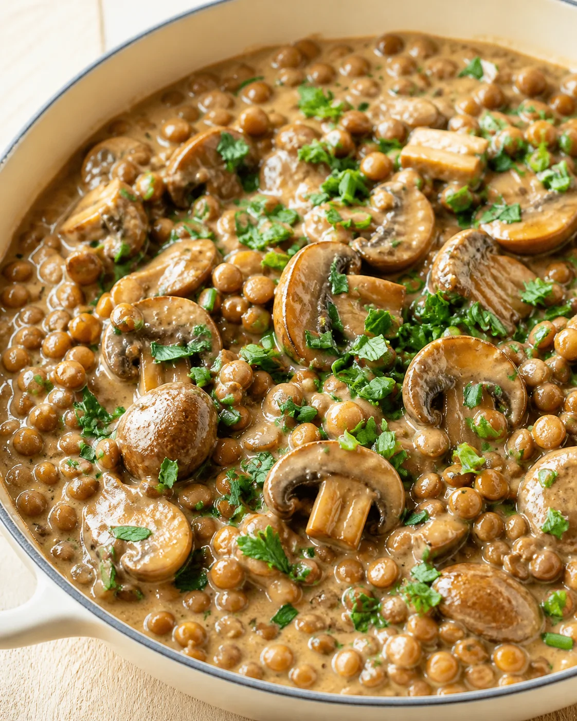 creamy mushroom and lentil stew in a light skillet, garnished with parsley