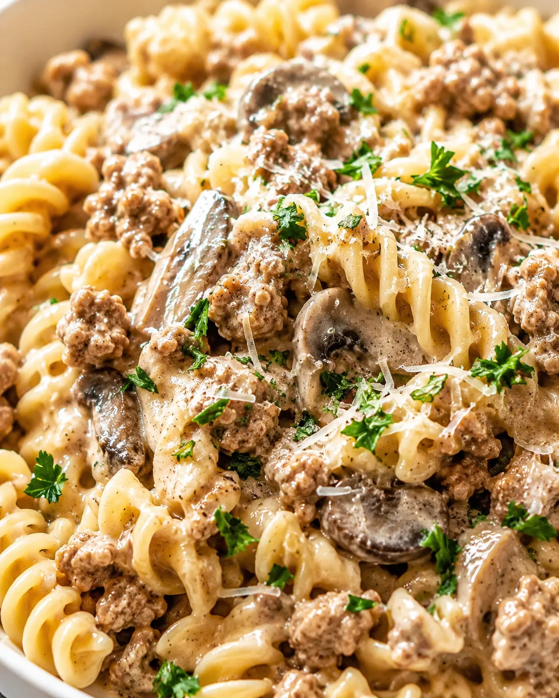 close-up of creamy sausage and mushroom pasta garnished with parsley and parmesan.