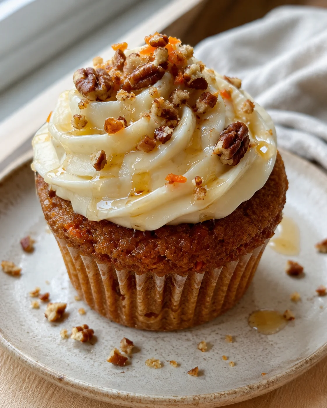 cupcake with white frosting swirls and chopped pecans on a ceramic plate
