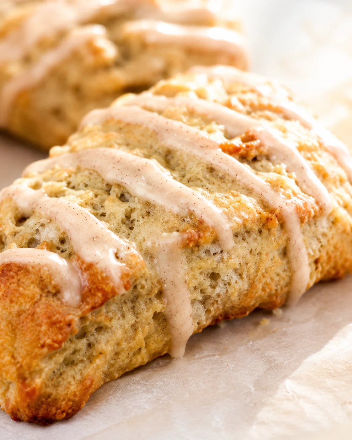 Close-up of a glazed cinnamon loaf slice with a soft, airy crumb on parchment