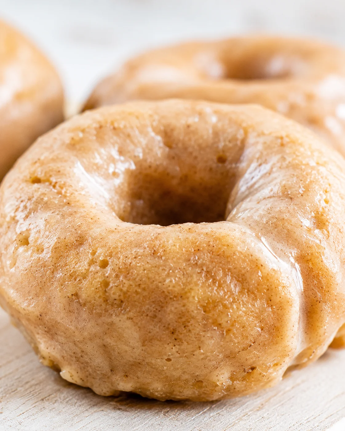 close-up of a golden glazed donut with shiny glaze on a wooden surface