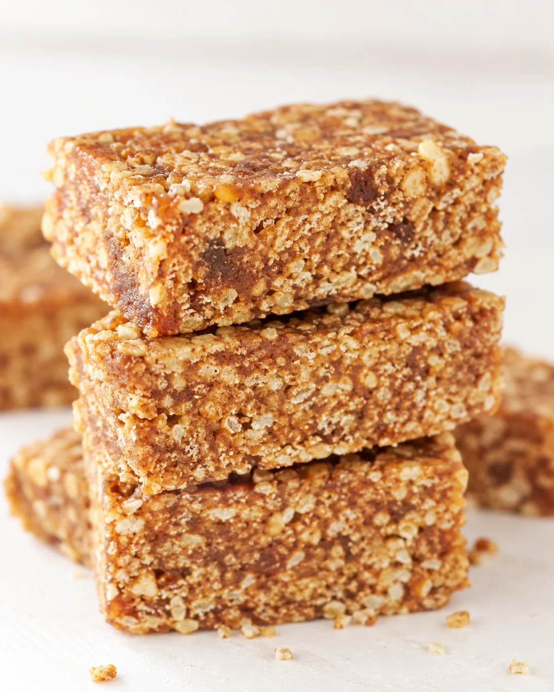 close-up of stacked granola bars with oats and nuts on a white surface