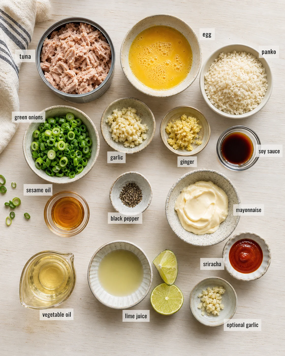 overhead view of labeled bowls with tuna, egg, green onions, and sauces on a light wood surface
