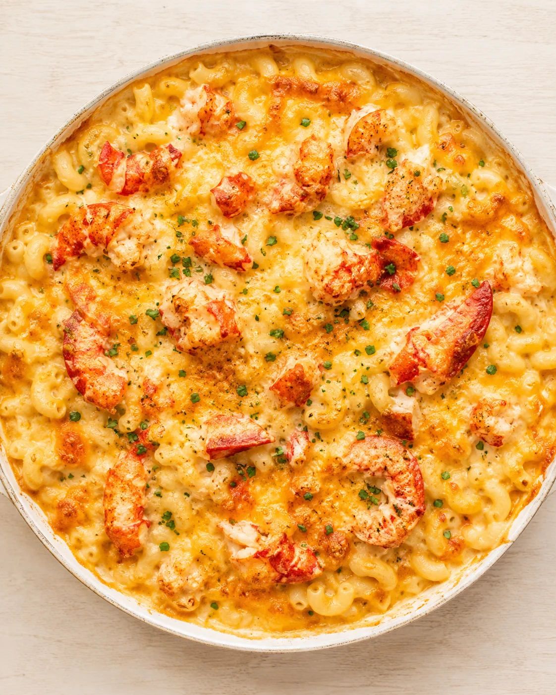 top-down view of creamy lobster macaroni and cheese in a skillet, topped with parsley