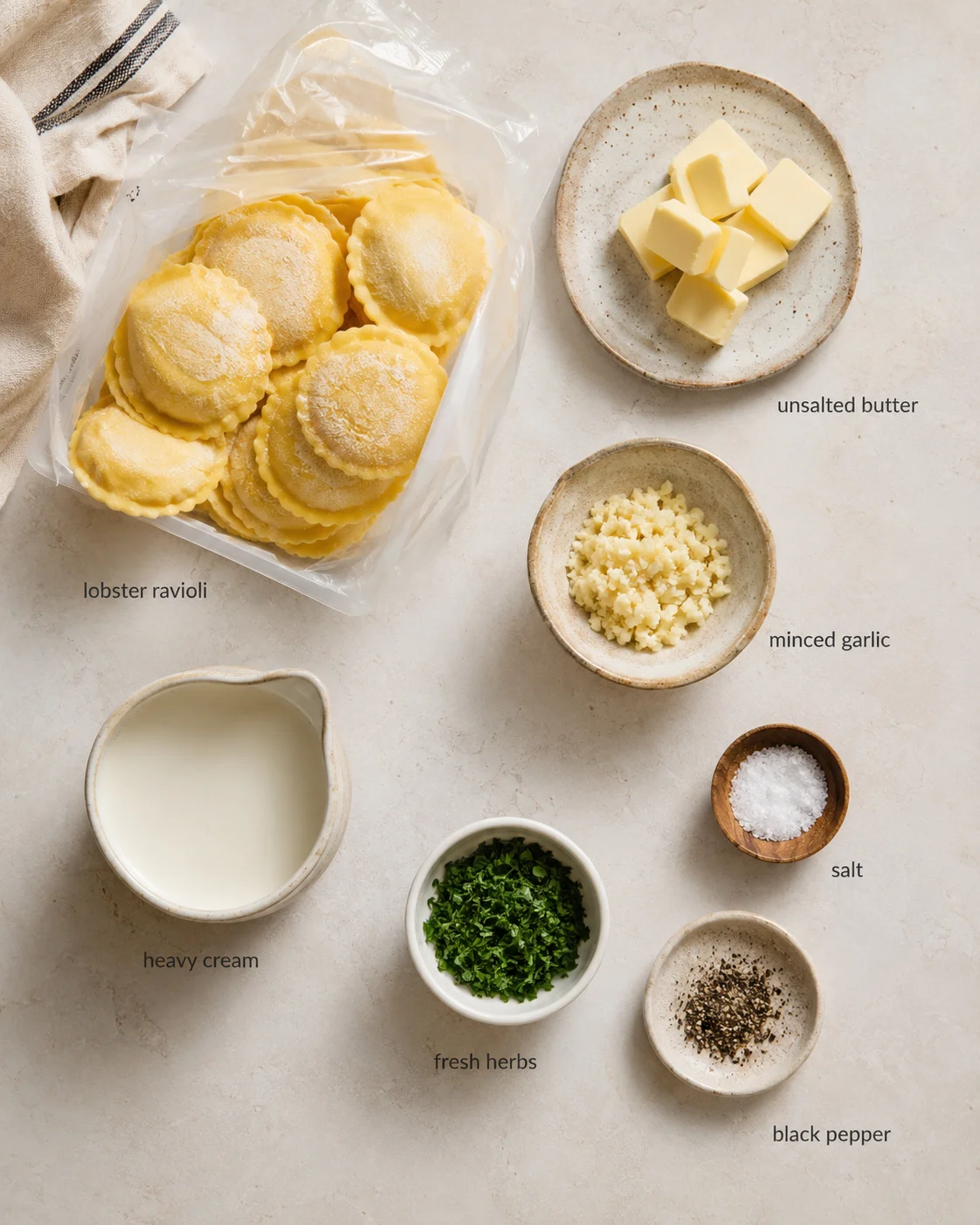 Top-down view of lobster ravioli and ingredients laid out with labels on a neutral countertop.