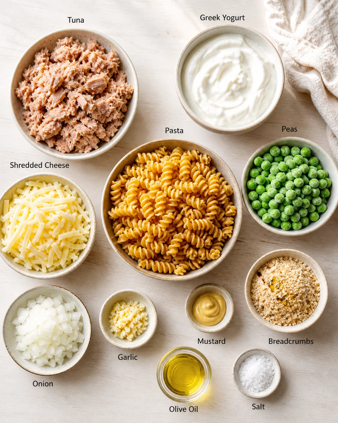 Overhead view of bowls with tuna, yogurt, pasta, peas, and cheeses.