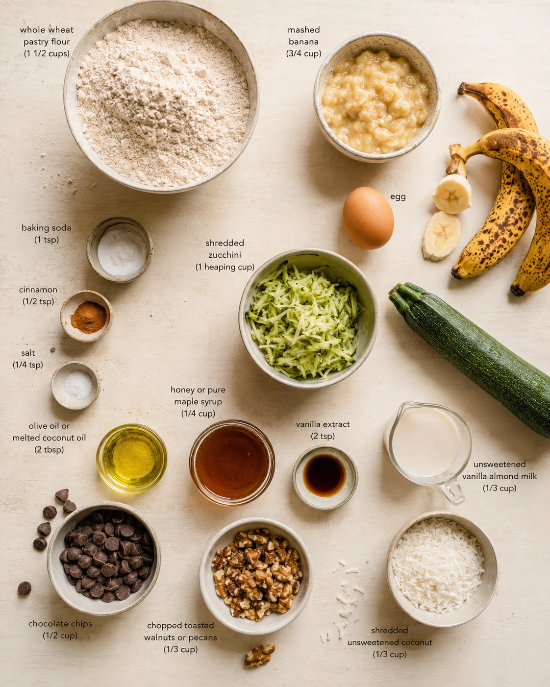 Overhead view of labeled baking ingredients arranged on a light neutral background.
