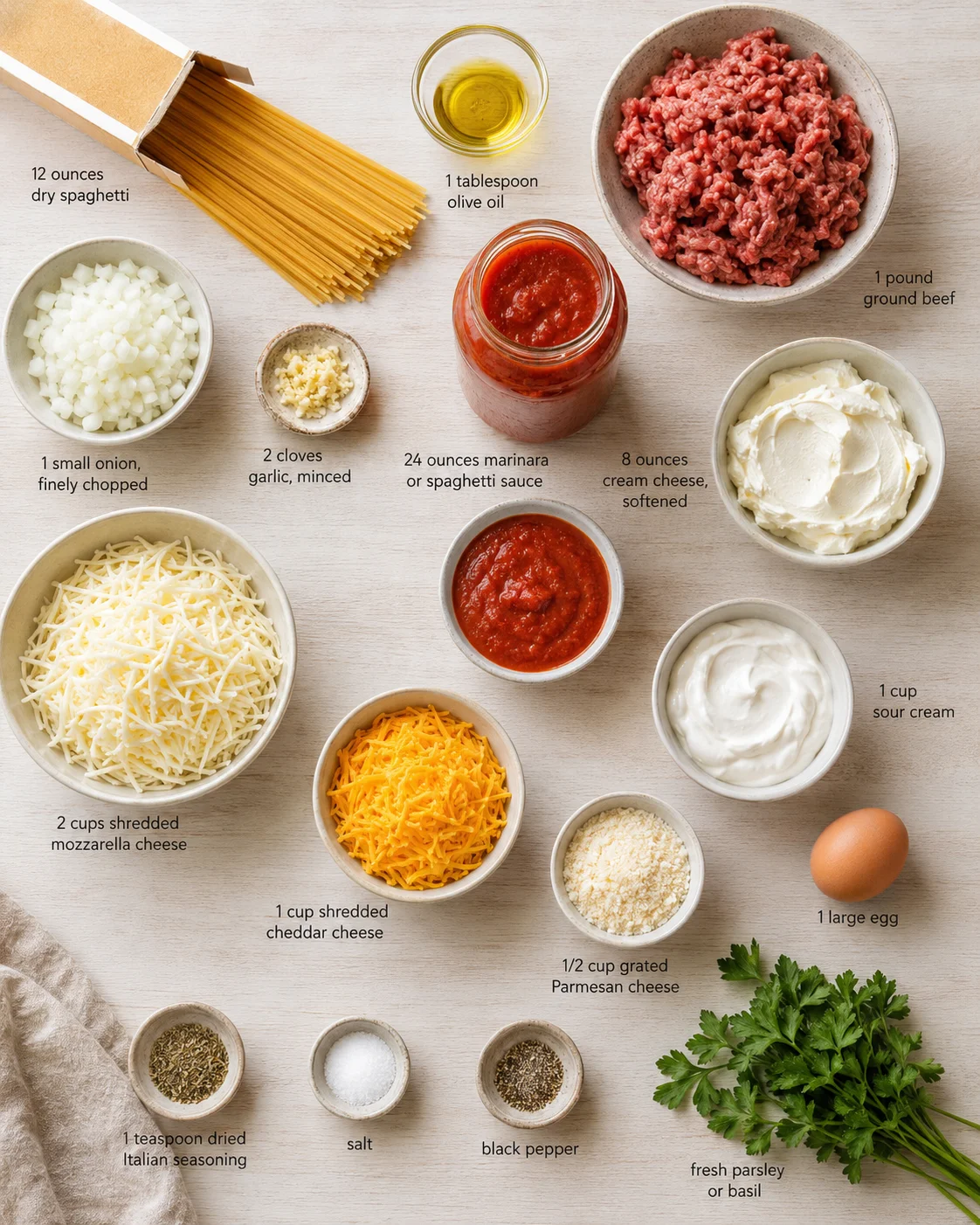 Top-down shot of labeled ingredients for spaghetti bake, including pasta, beef, cheeses, sauces, and herbs.