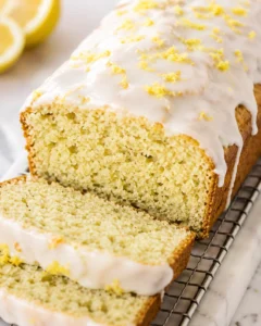 Close-up of lemon loaf cake with white glaze and lemon zest on top, sliced
