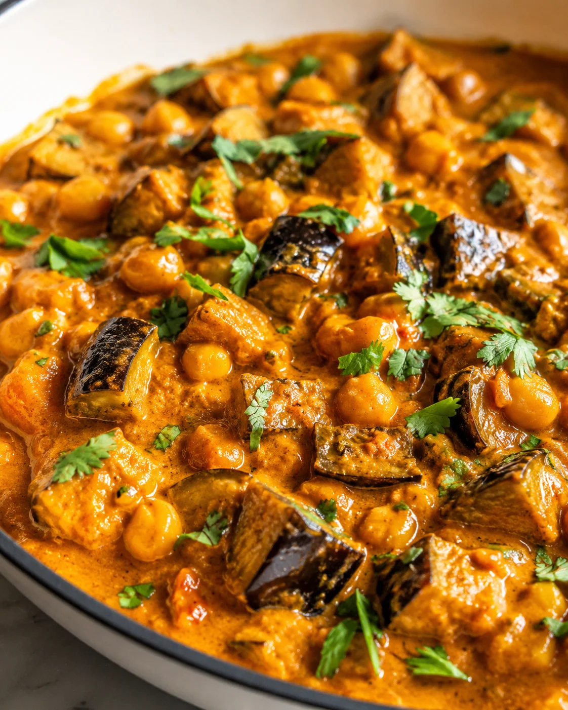 Delicious Eggplant Curry Close-up of hearty eggplant curry with chickpeas, herbs, and spices in a skillet