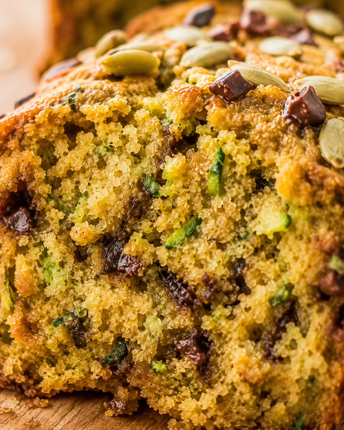 Gluten-Free Coconut Zucchini Bread Moist quick bread with zucchini, coconut, and chocolate chips on a wooden surface.