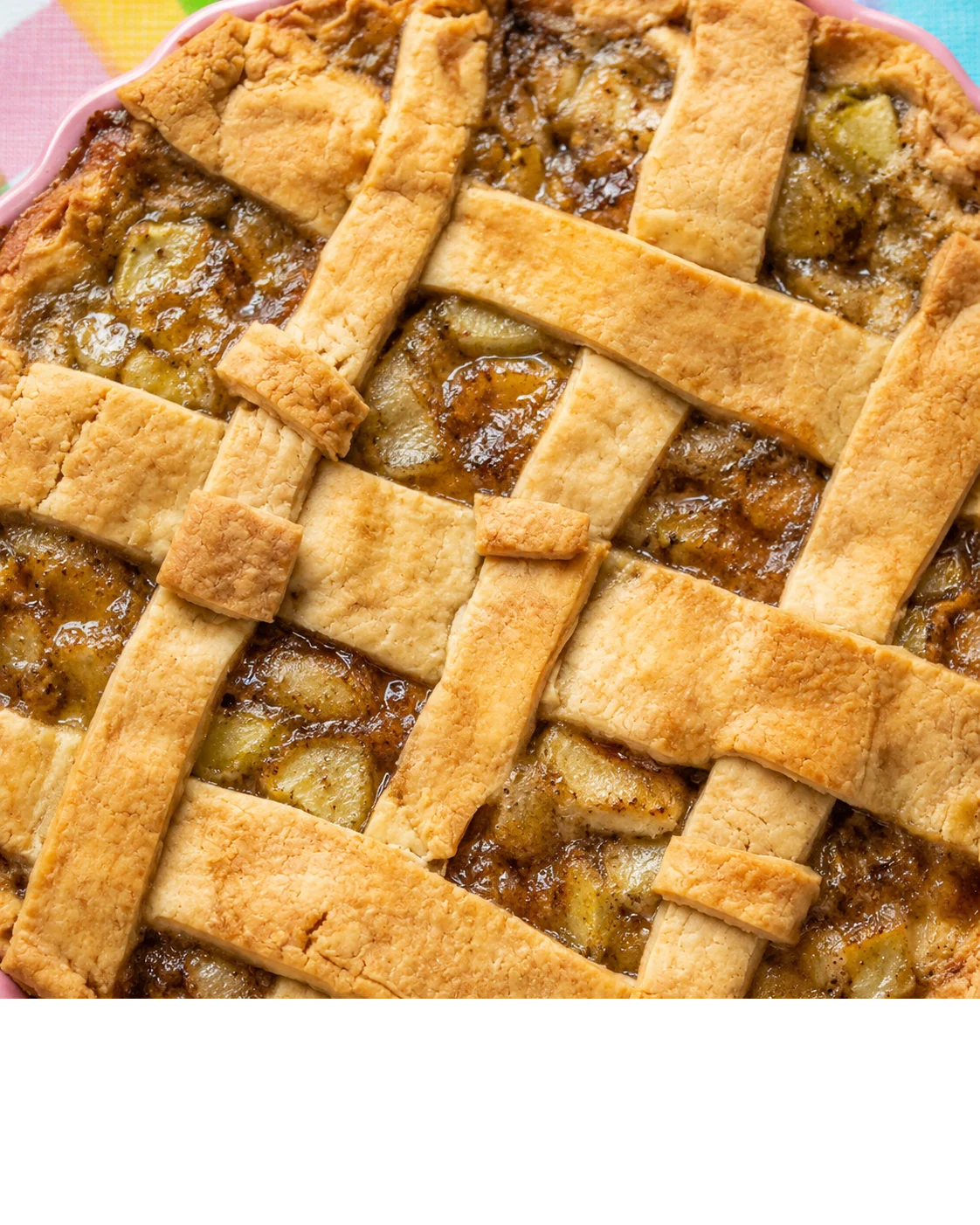 A close-up of a golden green tomato pie with a lattice crust, bubbling filling