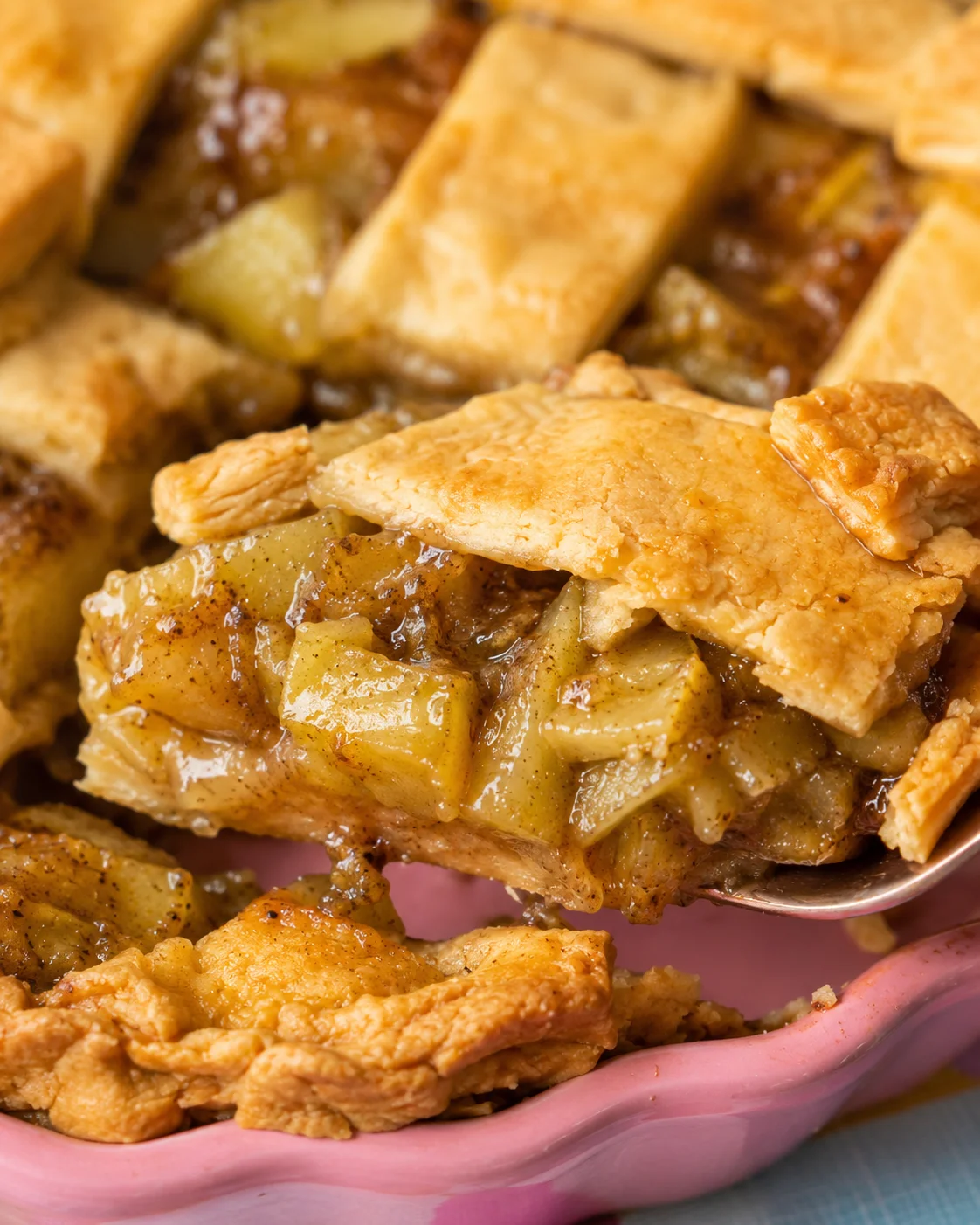 Close-up of green tomato pie with flaky crust and spiced filling in a pink dish