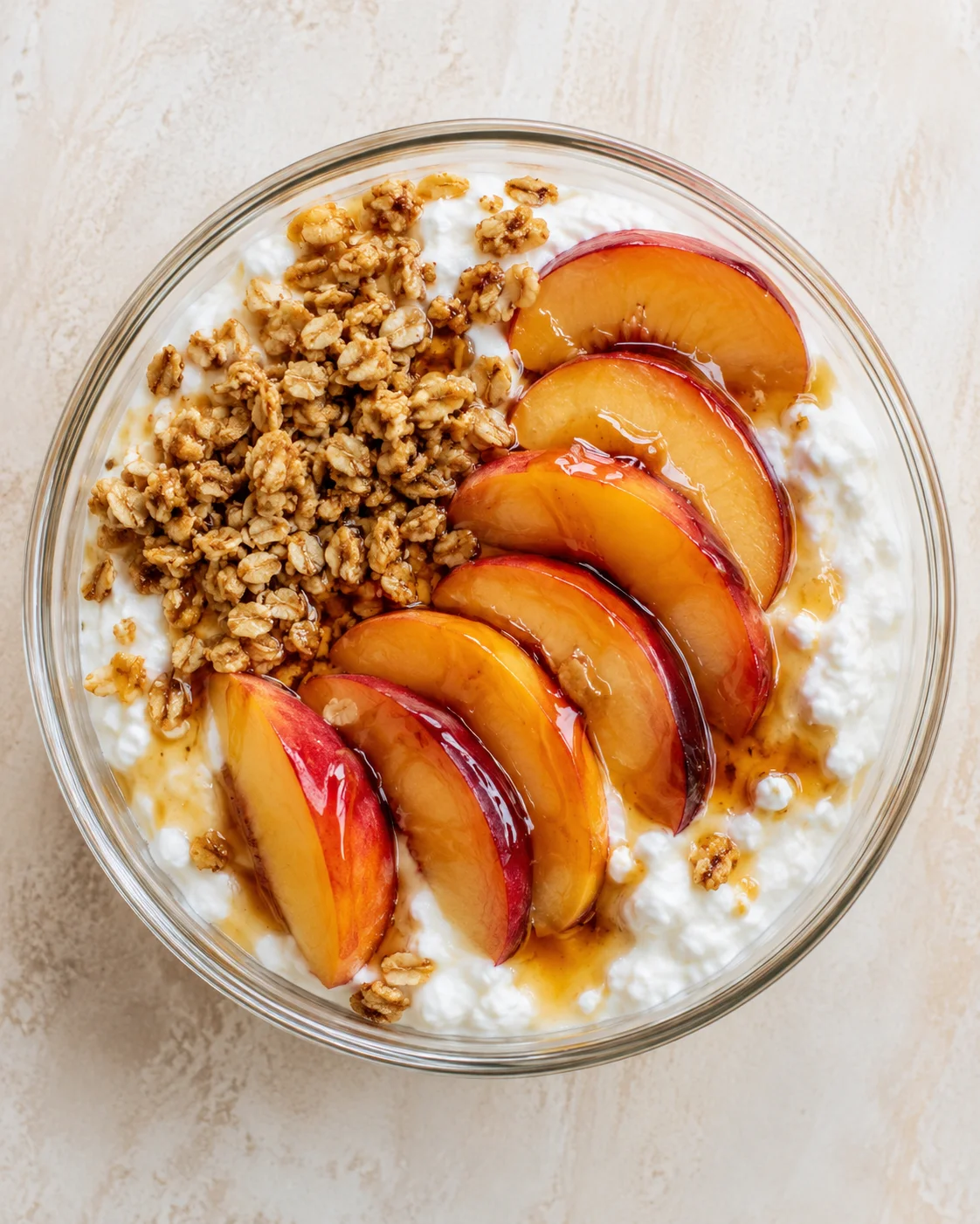 Top-down view of a yogurt bowl topped with peach slices and granola.