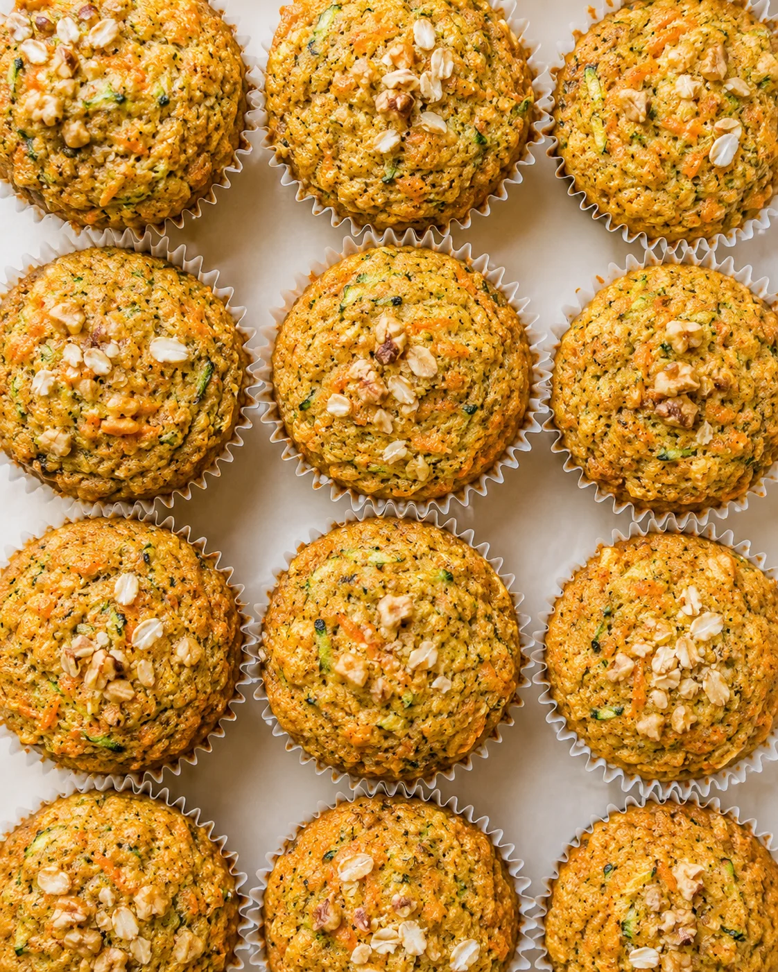 row of savory carrot muffins in white liners with chopped nuts