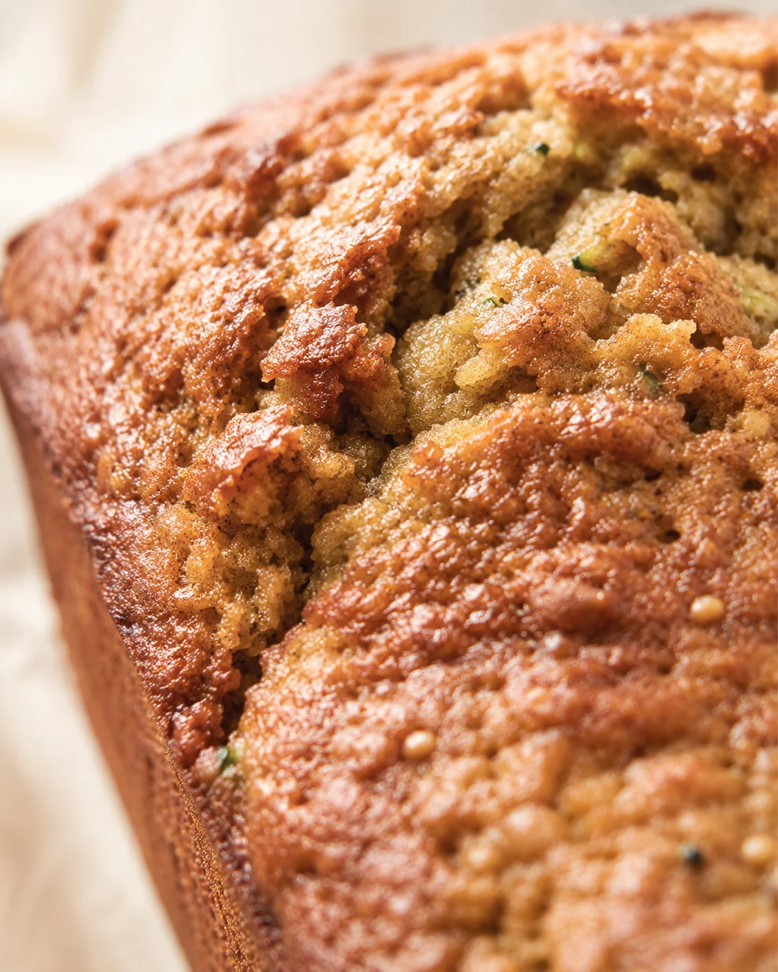 Close-up of a golden-brown loaf with a cracked crust and green specks in the moist crumb.
