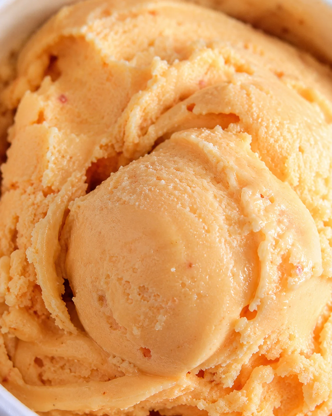 Creamy nectarine frozen yogurt with fresh nectarine pieces on top.