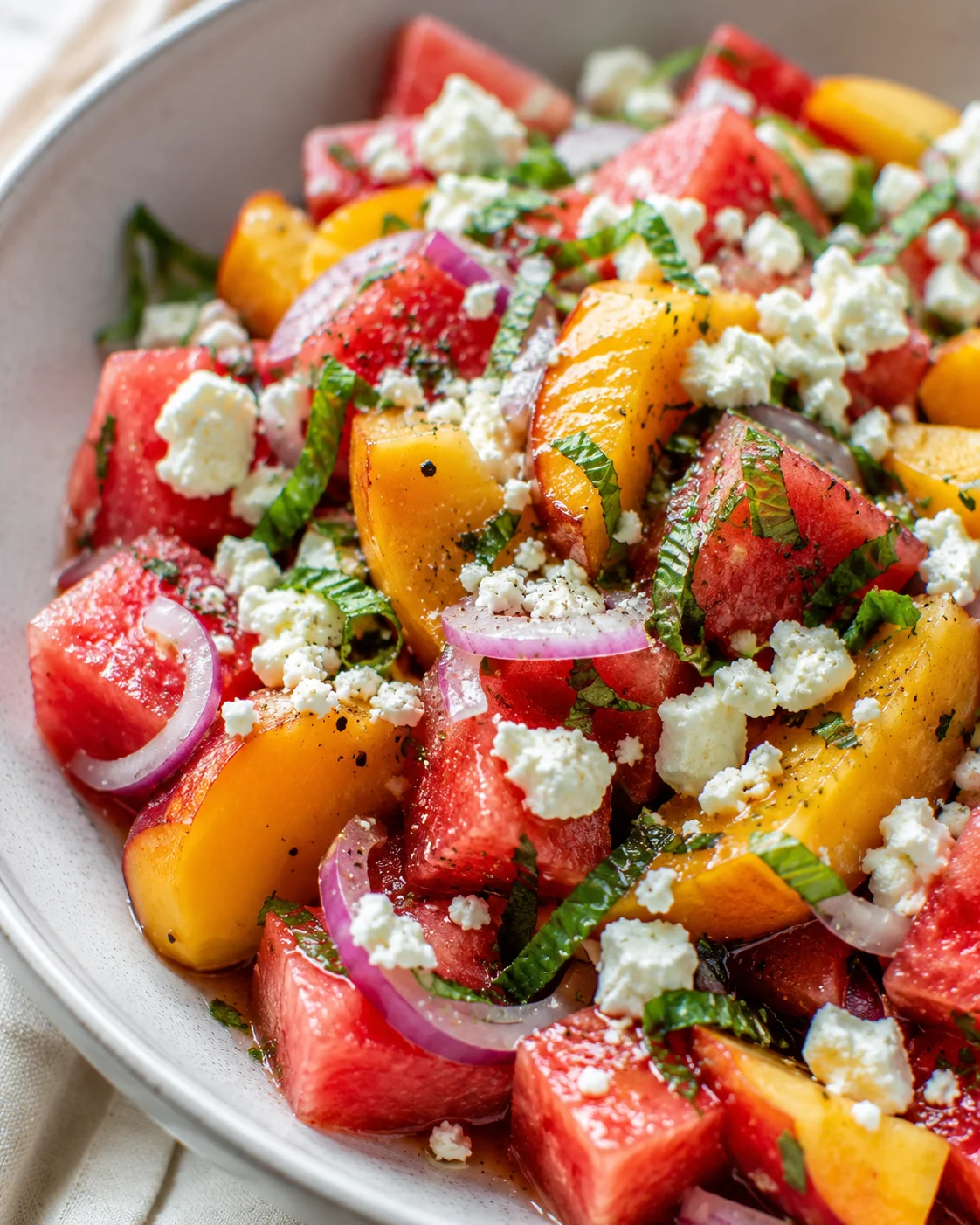 Colorful watermelon and peach salad with feta and herbs on a plate