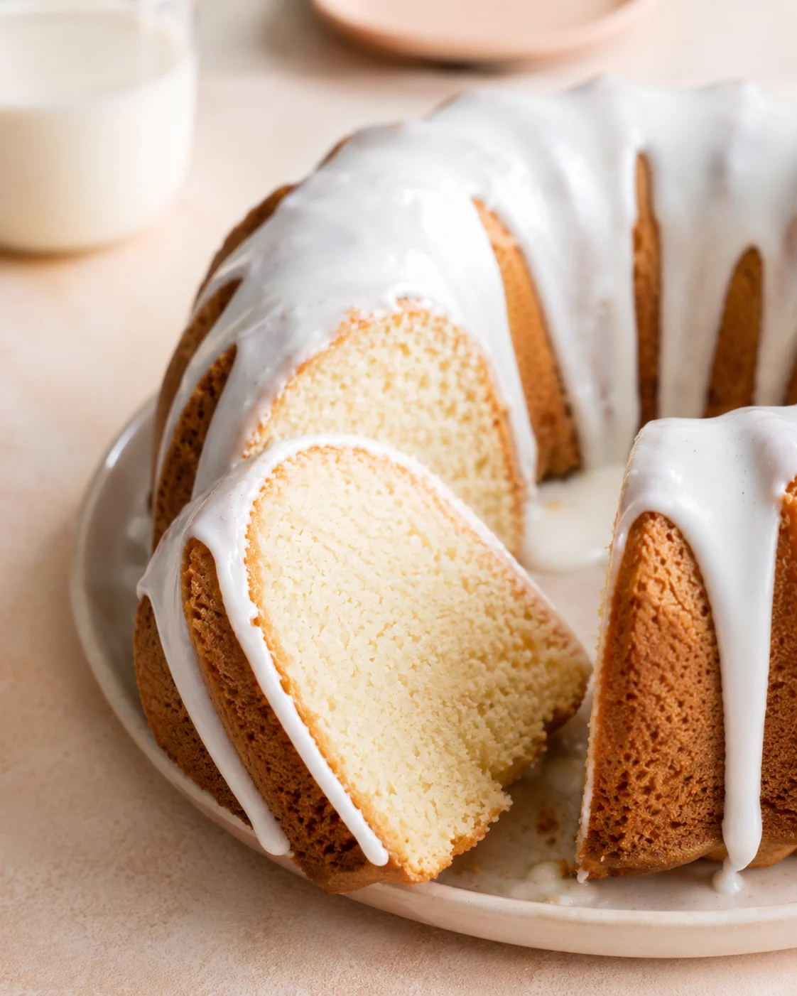 Close-up of a glazed vanilla bundt cake with a slice revealing tender crumb