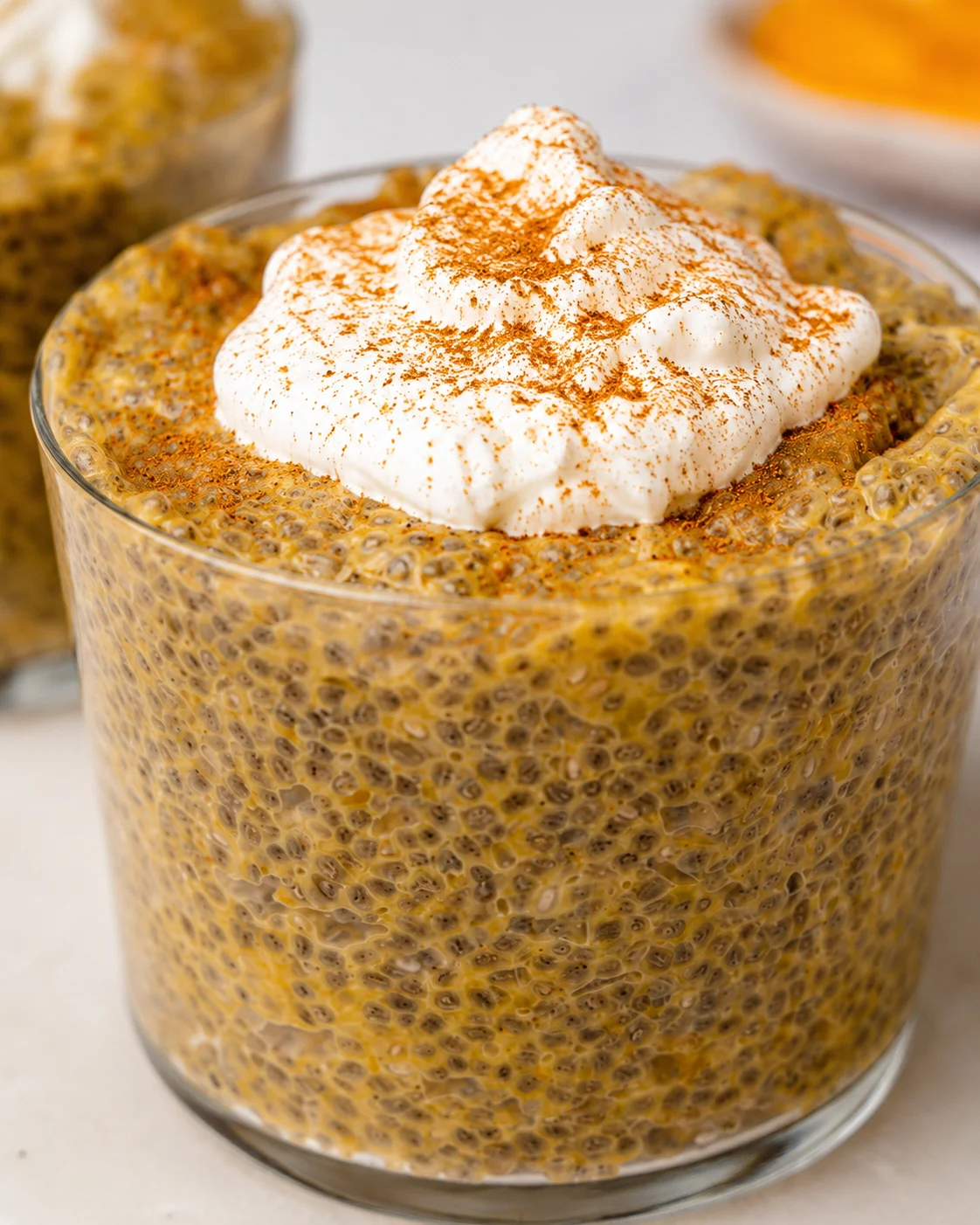 Creamy pumpkin chia pudding topped with whipped cream and a sprinkle of cinnamon.