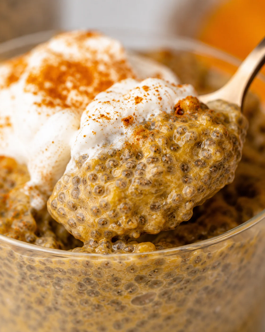 Close-up of creamy pumpkin chia pudding with whipped topping and cinnamon