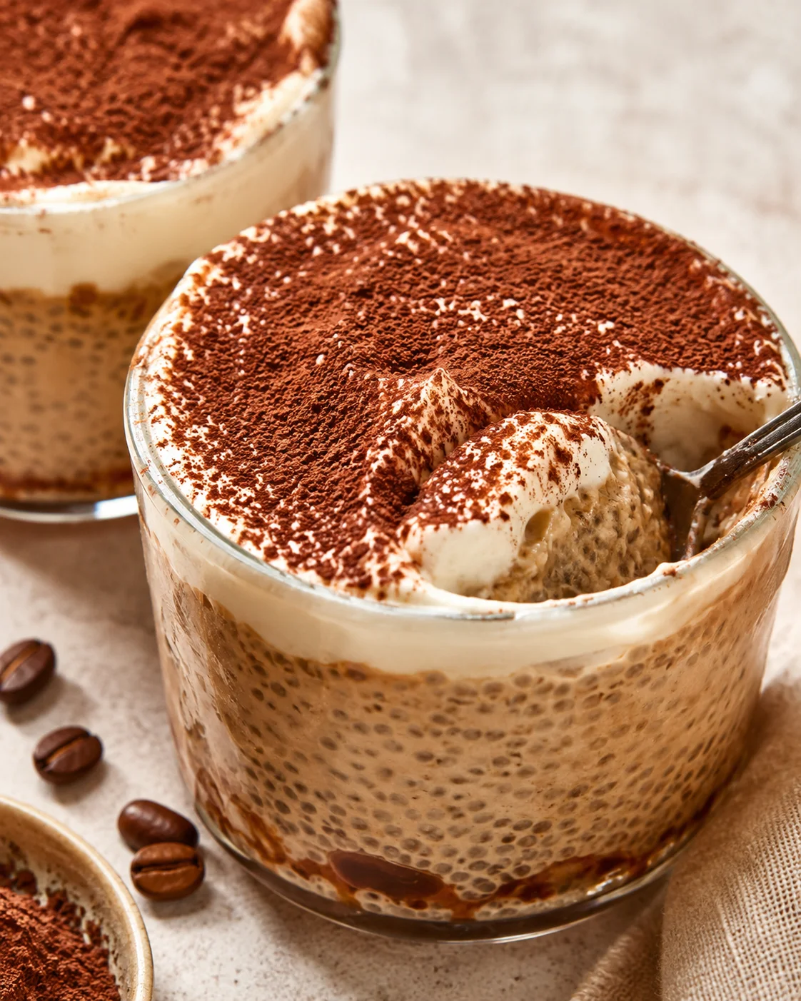 Delicious Tiramisu Chia Pudding Creamy tiramisu chia pudding topped with cocoa powder in glass cups